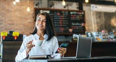woman sitting happily working with a smartphone in a coffee shop