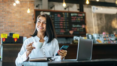 woman sitting happily working with a smartphone in a coffee shop
